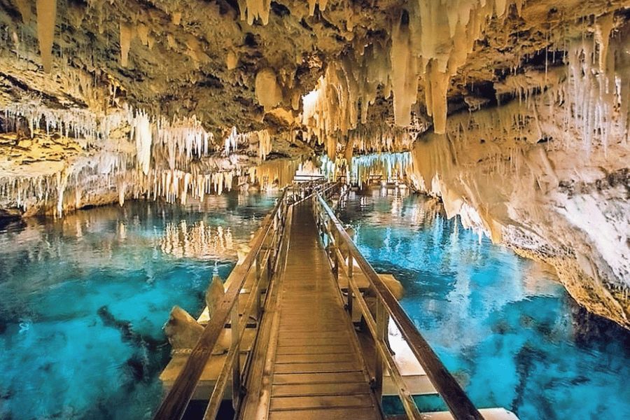 Pasarela de madera extendiéndose sobre aguas turquesas rodeada de estalactitas en la Cueva de Naica (México).
