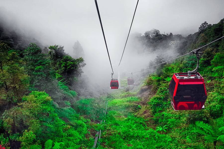 Cabinas rojas de un teleférico ascienden a través de una densa selva envuelta en niebla en Genting Highlands, Malasia.