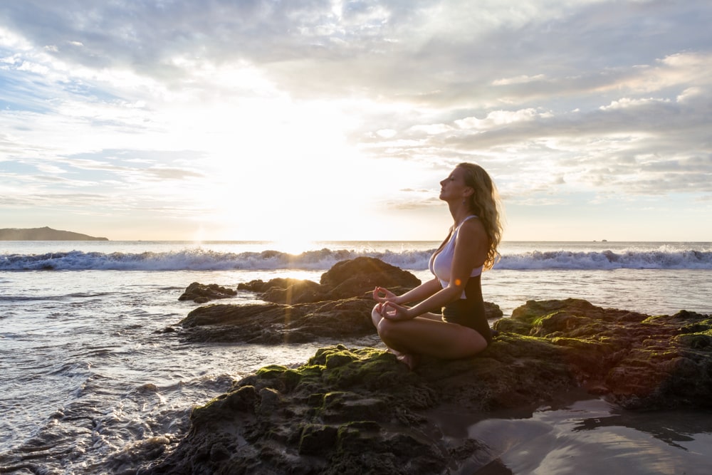 Mujer meditando sola en playa de Costa Rica