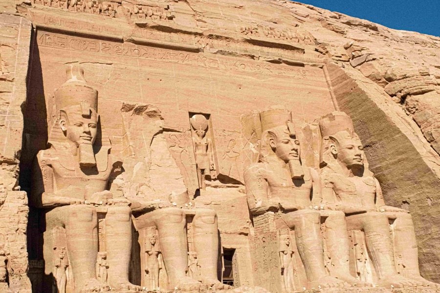 Cuatro estatuas colosales de Ramsés II se asientan majestuosas talladas en la fachada de roca del templo de Abu Simbel, bajo la luz directa del sol.