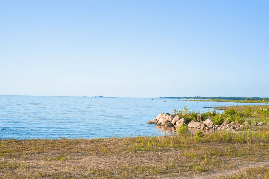 Lago Hurón: Costa rocosa del lago Hurón abriéndose hacia un amplio horizonte de aguas tranquilas y cielo claro.