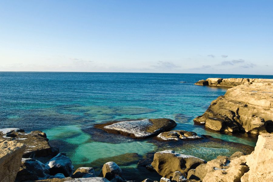Mar Caspio: Aguas turquesas y cristalinas del mar Caspio bañando una costa rocosa bajo un cielo despejado.