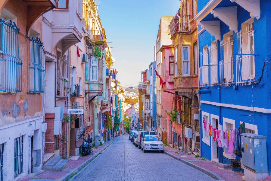 Edificios tradicionales de colores vivos flanquean una calle empedrada que se extiende hacia el fondo. Balat, estambul