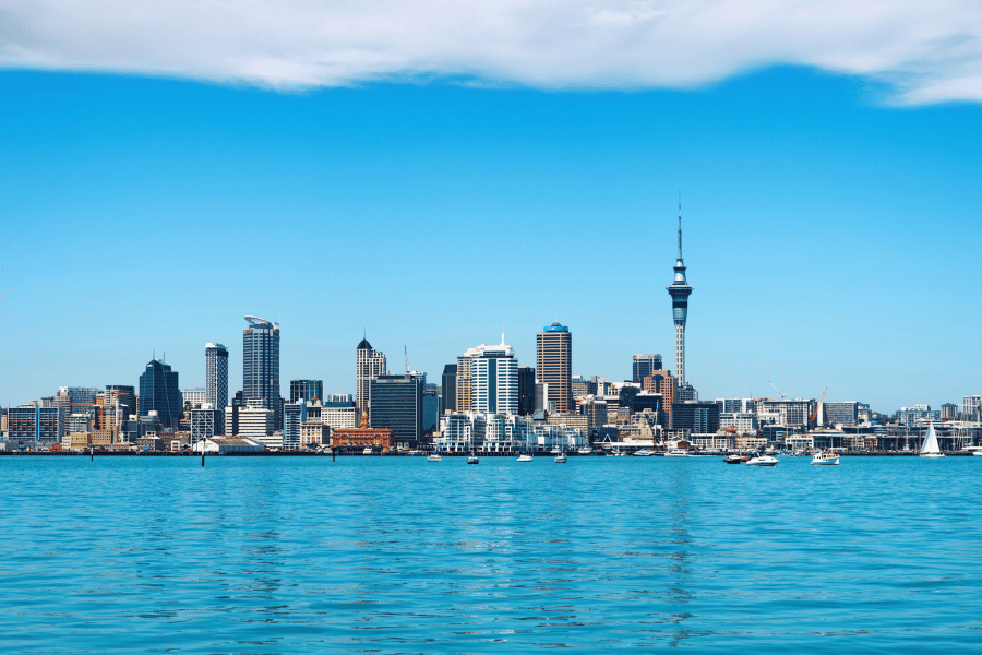 Rascacielos urbanos y la torre Sky Tower se alzan junto a aguas azules cristalinas bajo un cielo despejado en Auckland Nueva zelanda