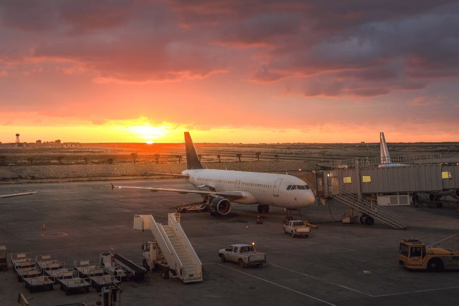 Aeropuerto de El Cairo, Egipto en la puesta de sol con cielo anaranjado y nubes bajas, un gran avión aparcado