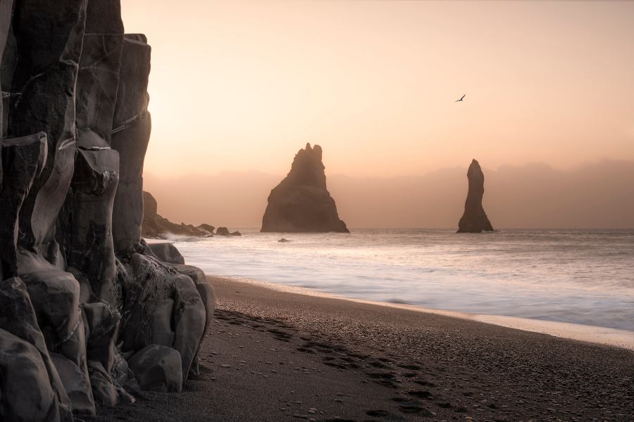 Playa de arena negra volcánica de Reynisfjara en Vík Islandia con las imponentes columnas de basalto de Gardar y picos rocosos en el mar.