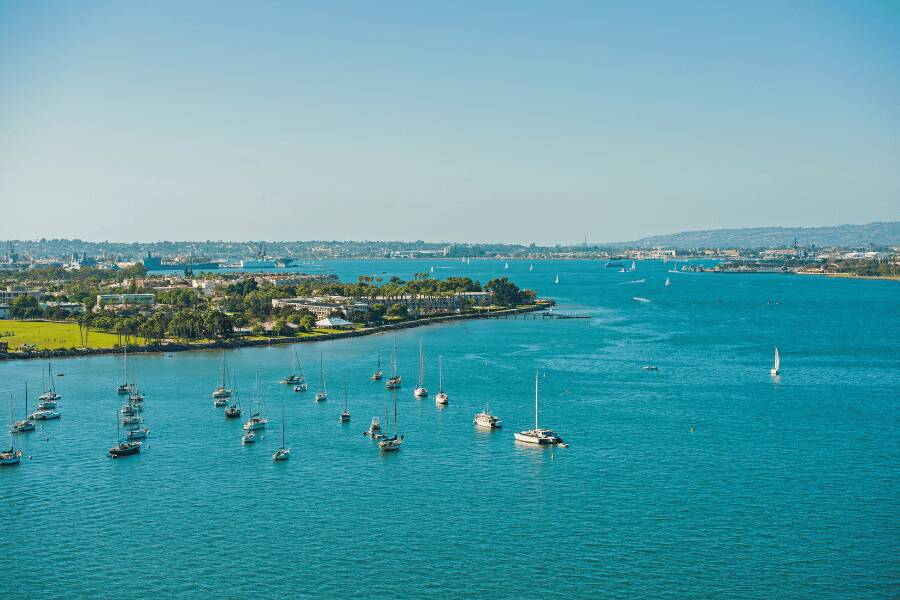 Coronado: Veleros anclados sobre el agua azul de la bahía con la costa al fondo en Coronado, San Diego.