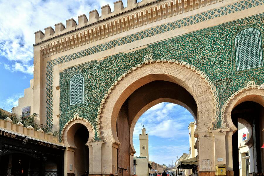 La gran puerta monumental de Bab Bou Jeloud se alza decorada con azulejos verdes y arcos de herradura, dando acceso a una calle histórica en la medina de Fez. Bab Bou Jeloud Gate in Fes Morocco.