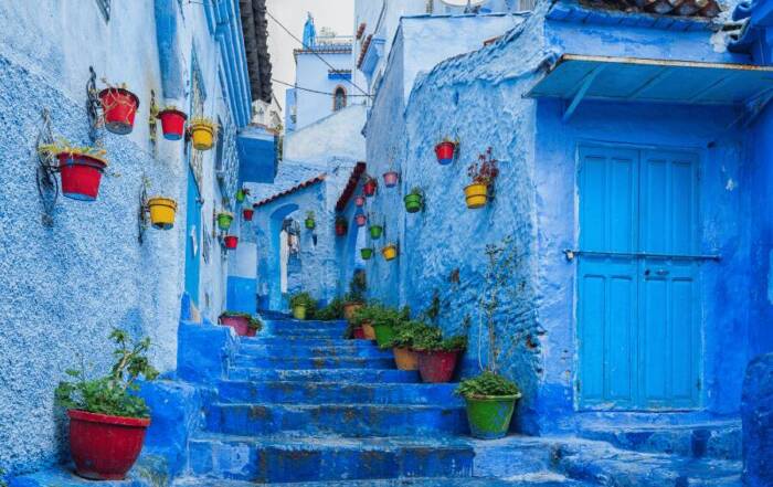 marruecos que visitar Una pintoresca escalera de piedra sube entre fachadas y macetas de plantas en un callejón empedrado teñido por entero de azul. Chefchaouen, Morocco.