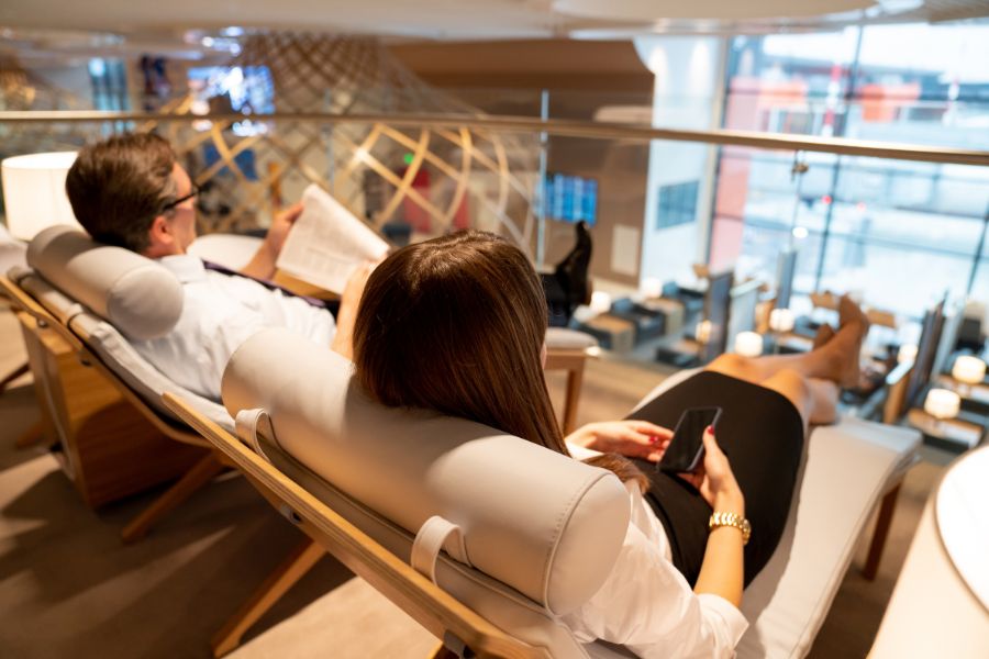 sala vip aeropuerto dos personas tumbadas leyendo y con el telefono