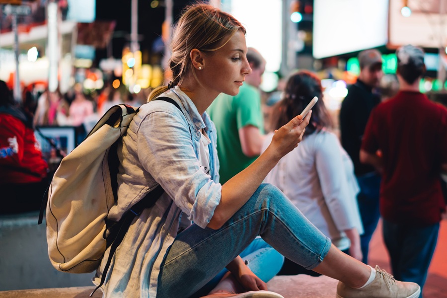 Chica sentada en Times Square usando la mejor eSIM para Estados Unidos.