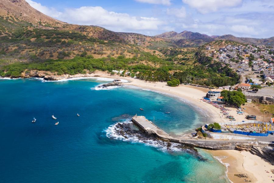 vista aérea de la Playa de Tarrafal, en la isla de santiado, Cabo Verde, africa, conbarcos pequeños en un mar azul cristalino y montañas jutno a un pueblo de casas blancas