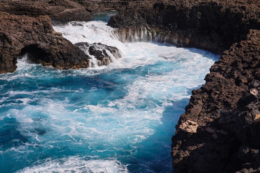 Oleaje intenso rompiendo con fuerza y creando espuma blanca sobre las rocas volcánicas oscuras en la bahía de Buracona, Cabo Verde.