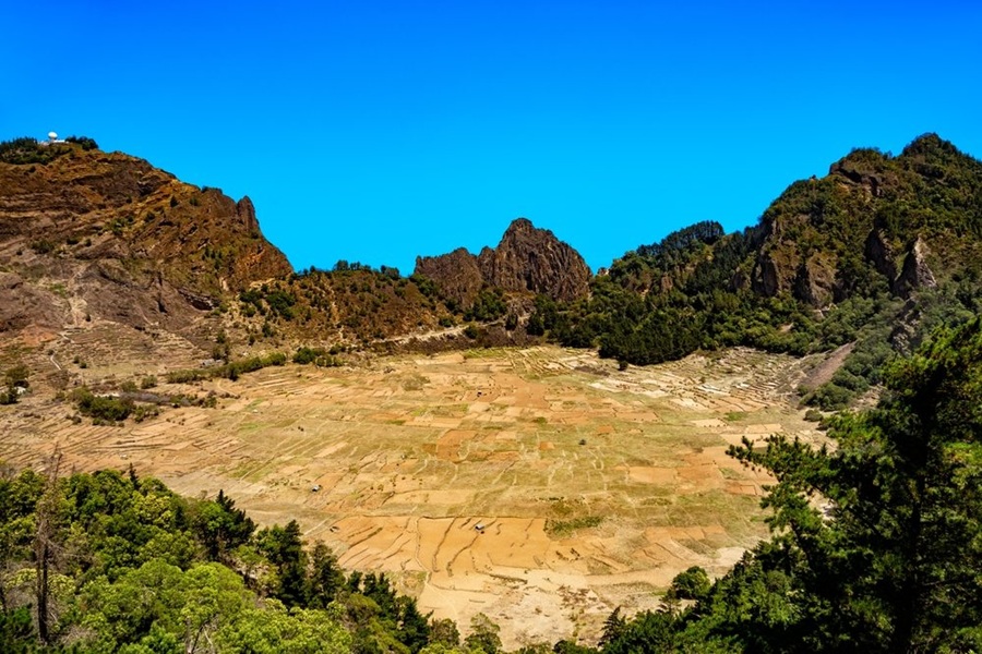 Campos agrícolas trazados en el interior del gran cráter volcánico Cova de Paul, rodeados de laderas rocosas y vegetación en la isla de Santo Antão, Cabo Verde.