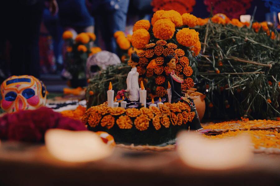 Una ofrenda decorada con flores de cempasúchil, calaveras de azúcar y velas encendidas reposa sobre un altar iluminado.