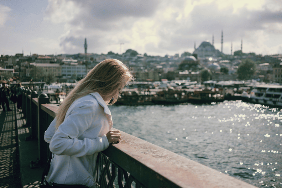 Una joven observa el paisaje urbano y marino apoyada en la barandilla de un puente en Estambul, Turquía